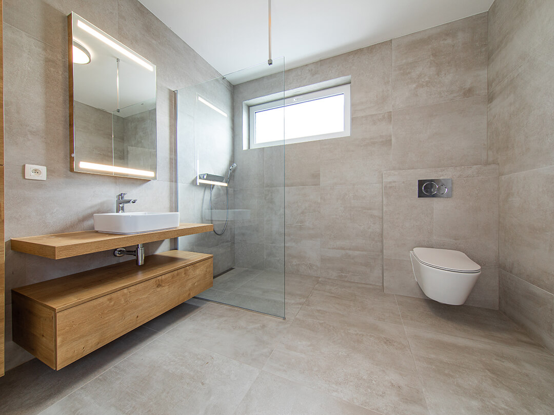Barrierefreie Walk-in-Dusche bestehend aus einer Glaswand zwischen Waschbecken und Fenster