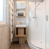 Blick in das Badezimmer mit Eckdusche, Wascharmatur, Spiegelschrank und Heizung