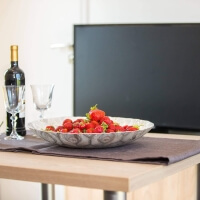 Schale mit Erdbeeren, Wein und Weingläsern vor dem Flatscreen TV