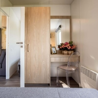 Schreibtisch mit Spiegel und Schreibtischstuhl neben dem geräumigen Kleiderschrank