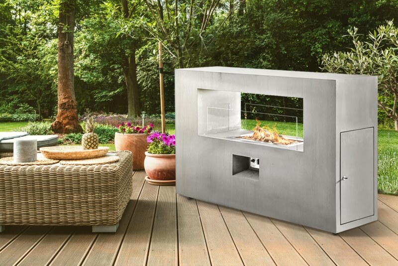 Dekokamin aus Edelstahl als Dekoelement im Garten neben Sitzgruppe