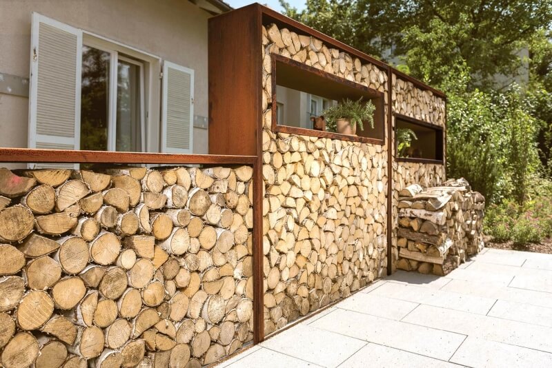 Kaminholzregale aus Cortenstahl dienen als Sichtschutz auf der Terrasse