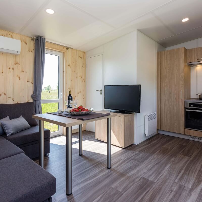 Wohnbereich mit Sofa, Tisch und Sideboard mit Flatscreen TV