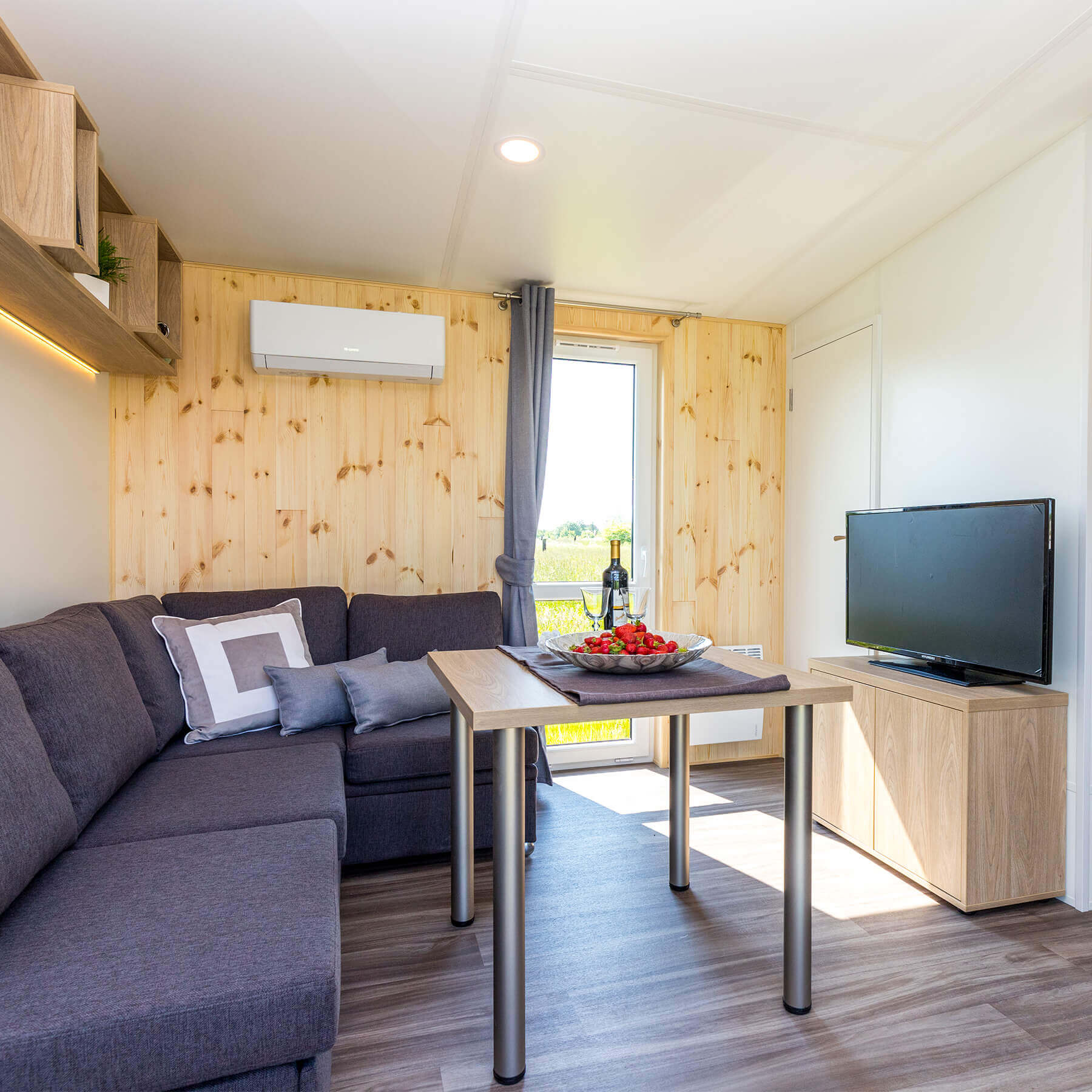 Wohnbereich mit Sofa, Couchtisch, Sideboard und Fernseher. 